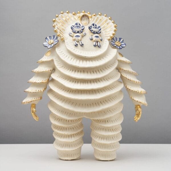 a ceramic figure with a scalloped suit, gold hands, and two floral figures for eyes
