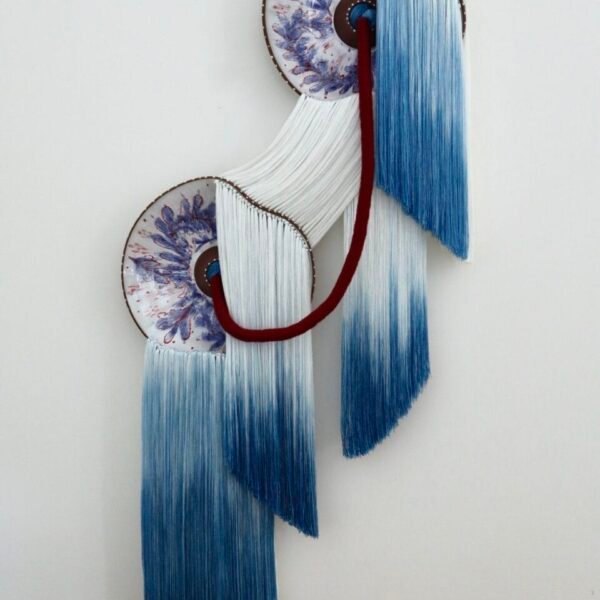 تركيب جداري مصنوع باستخدام ألياف باللونين الأزرق والأبيض وألواح سيراميك مزججة باللونين الأزرق والأبيض مع توصيل الألياف من خلال فتحات في الألواح ولفها بشكل أنيق