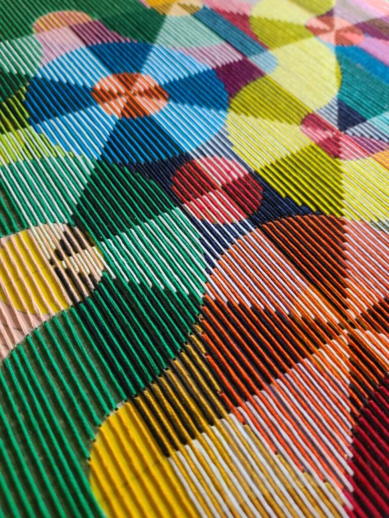 a detail of an abstract, geometric thread composition on a wood panel