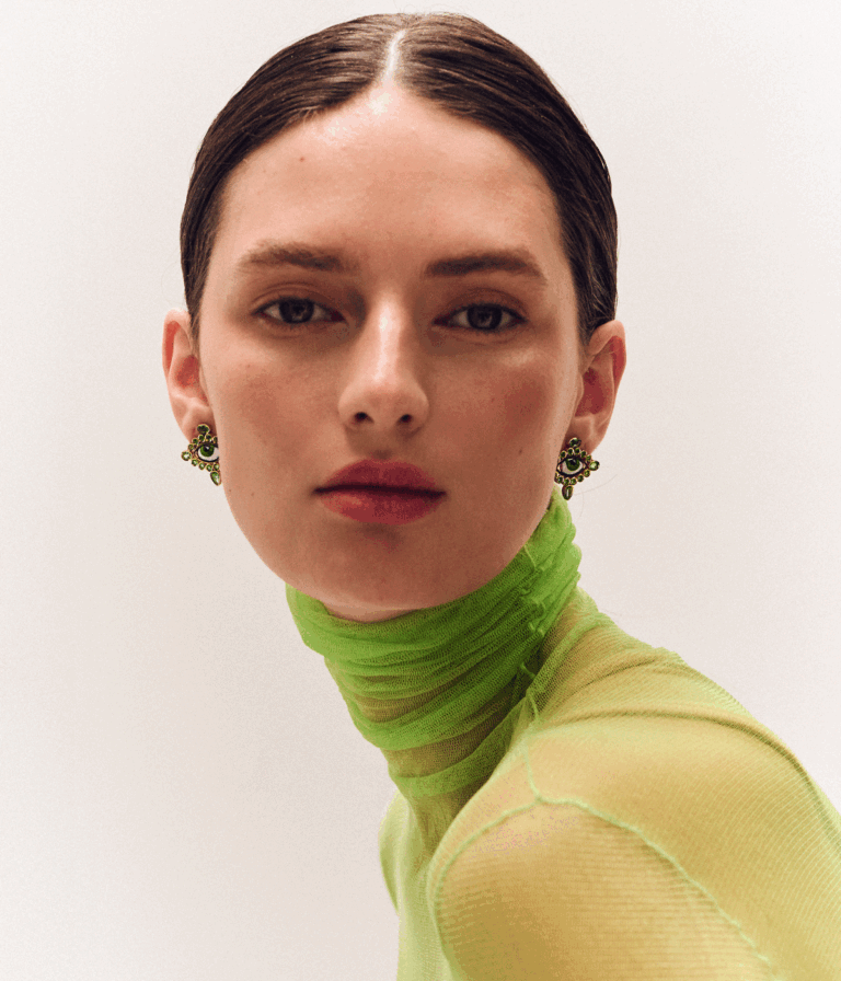 امرأة في قمة خضراء ترتدي أقراط