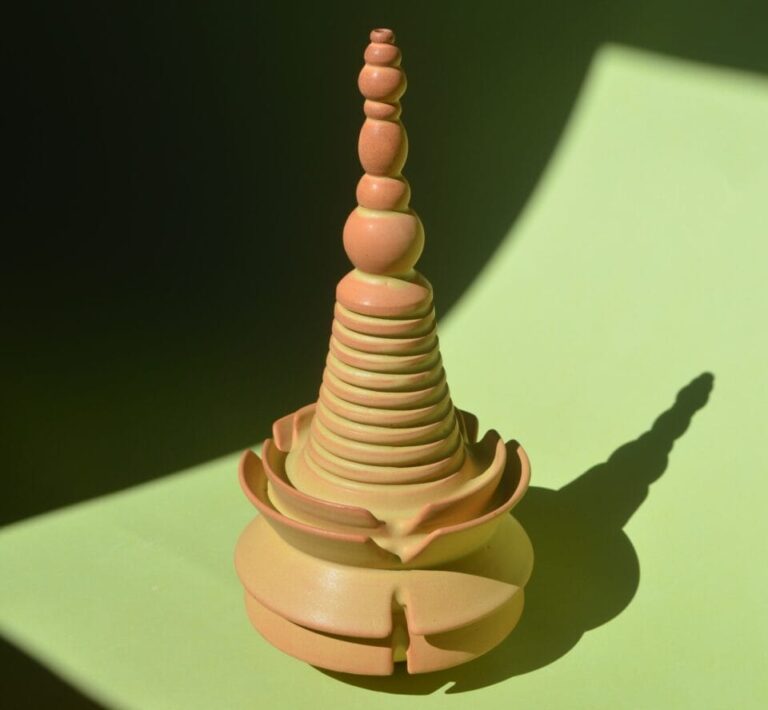 a geometric beige and peach-colored sculpture with ribbed walls, stacked spheres, and concentric circle forms