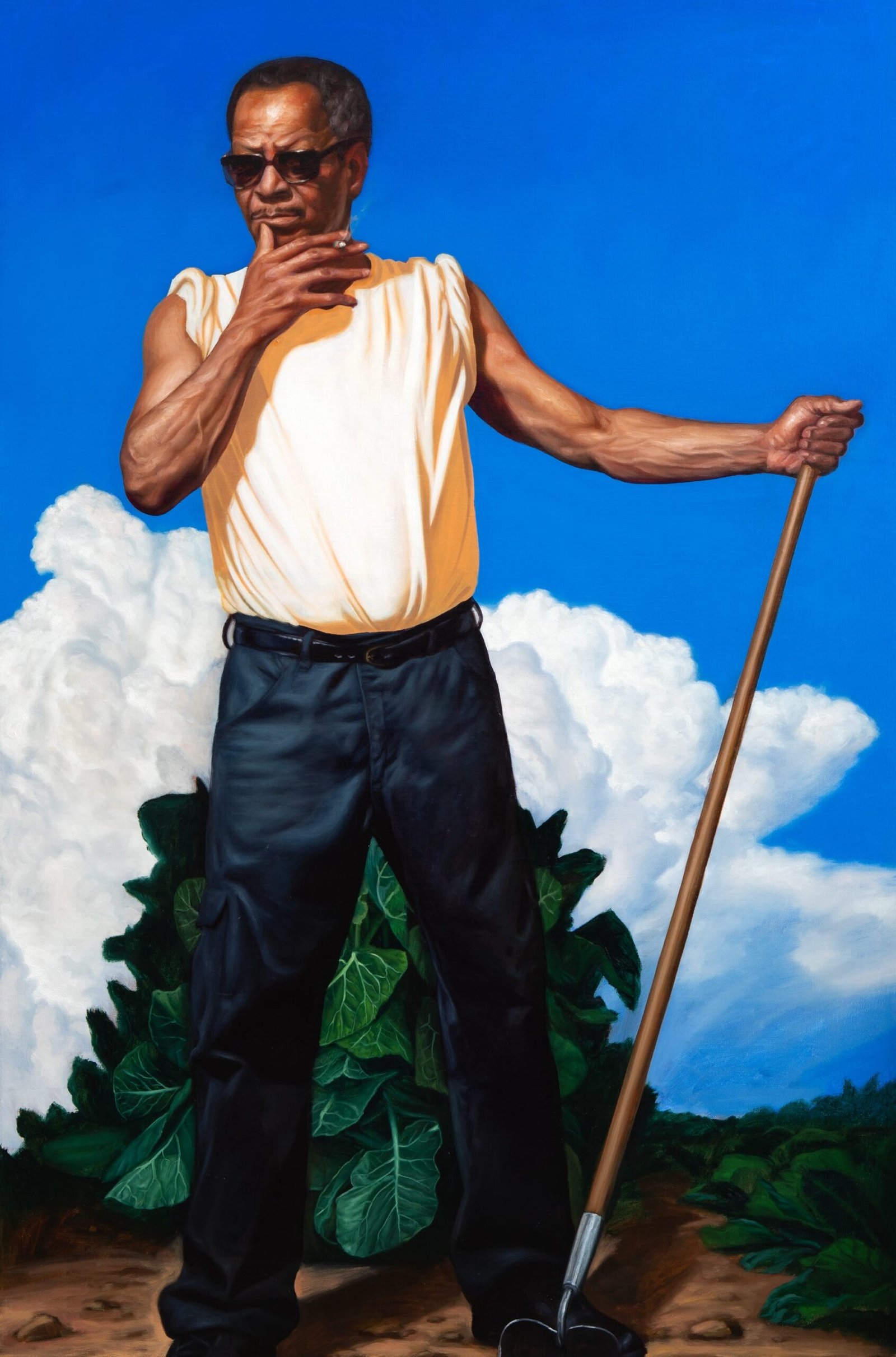 a Black man stands in a garden or field, holding a hoe, against a blue sky