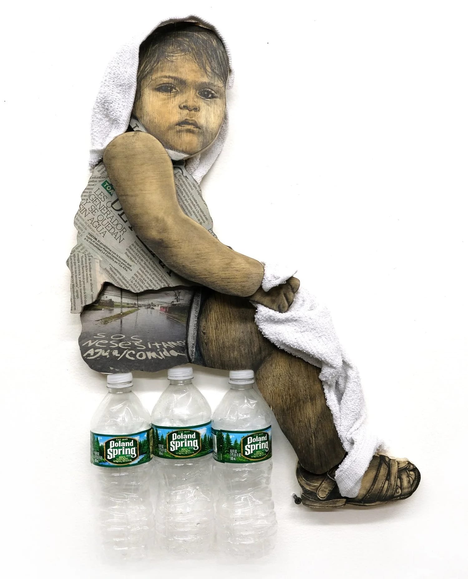 a portrait of a child sitting on three plastic water bottles with a white cloth towel over their head