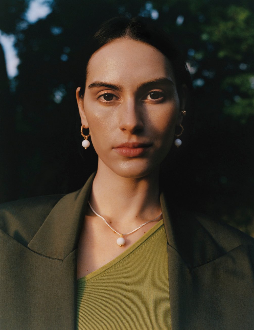 woman wearing necklace and earrings stood outside