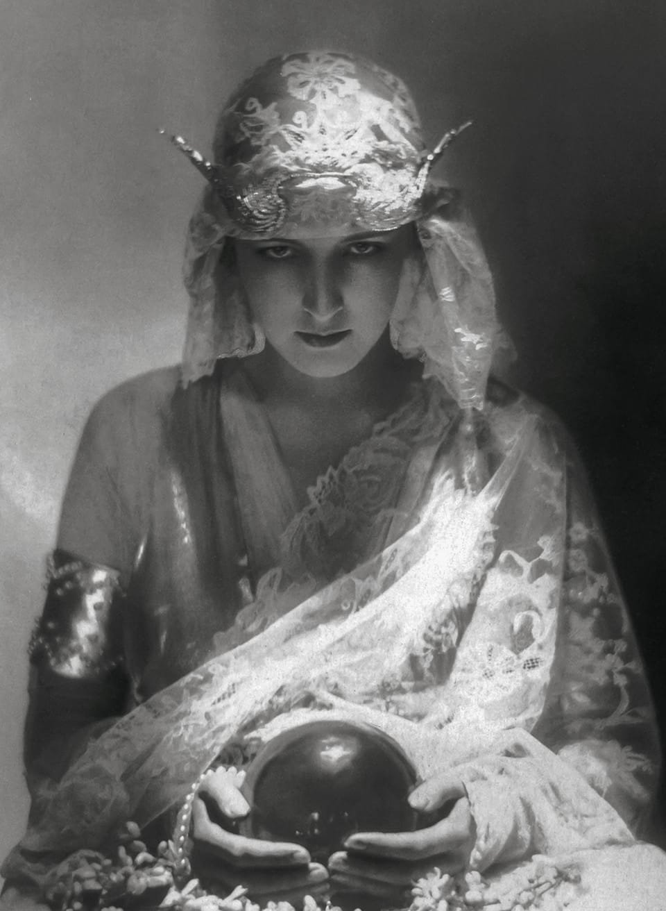 صورة بالأبيض والأسود لامرأة في فستان في العشرينات من القرن العشرين ، تحمل كرة بلورية