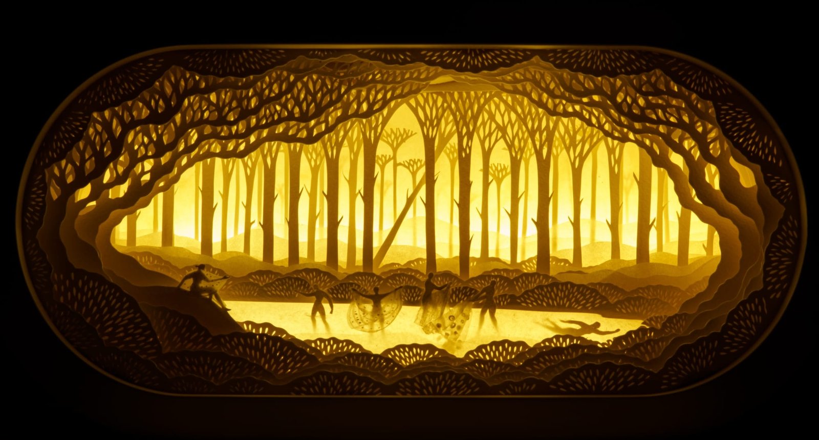 an illuminated paper cut scene by Hari and Deepti depicting tiny figures in a dense forest landscape