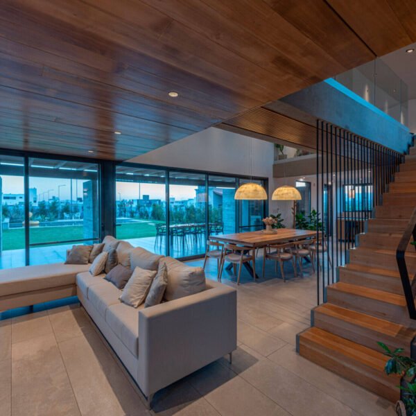 Inside, the living room forms part of the open social space, alongside the dining area and kitchen. A double-height window opens to the north, overlooking the entrance courtyard and drawing in sunlight throughout the day. 