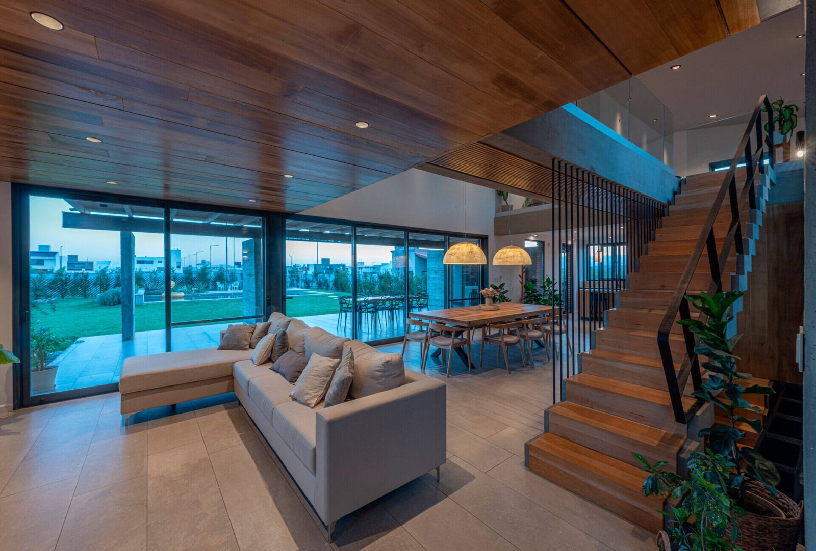 Inside, the living room forms part of the open social space, alongside the dining area and kitchen. A double-height window opens to the north, overlooking the entrance courtyard and drawing in sunlight throughout the day.