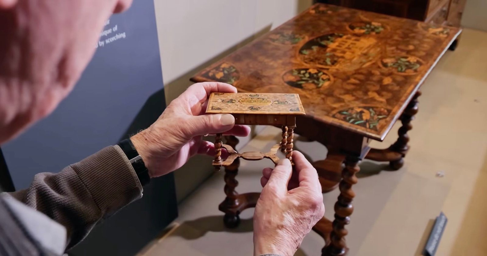 تيري فيسي يكرر بشق الأنفس طاولة مطعمة من القرن السابع عشر بمقياس 1:8 1 لقطة ثابتة من فيلم وثائقي قصير أنتجه متحف فيكتوريا وألبرت لنسخة مصغرة طبق الأصل من طاولة من القرن السابع عشر ذات أرجل ملتوية موضوعة أمام النسخة الأصلية