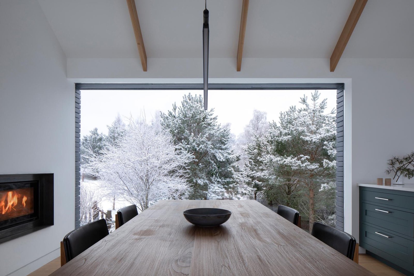 A large picture window in the dining area frame the surrounding trees, turning the landscape into a natural backdrop.