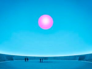 a large-scale light exhibition by James Turrell featuring a pink hole in a blue dome