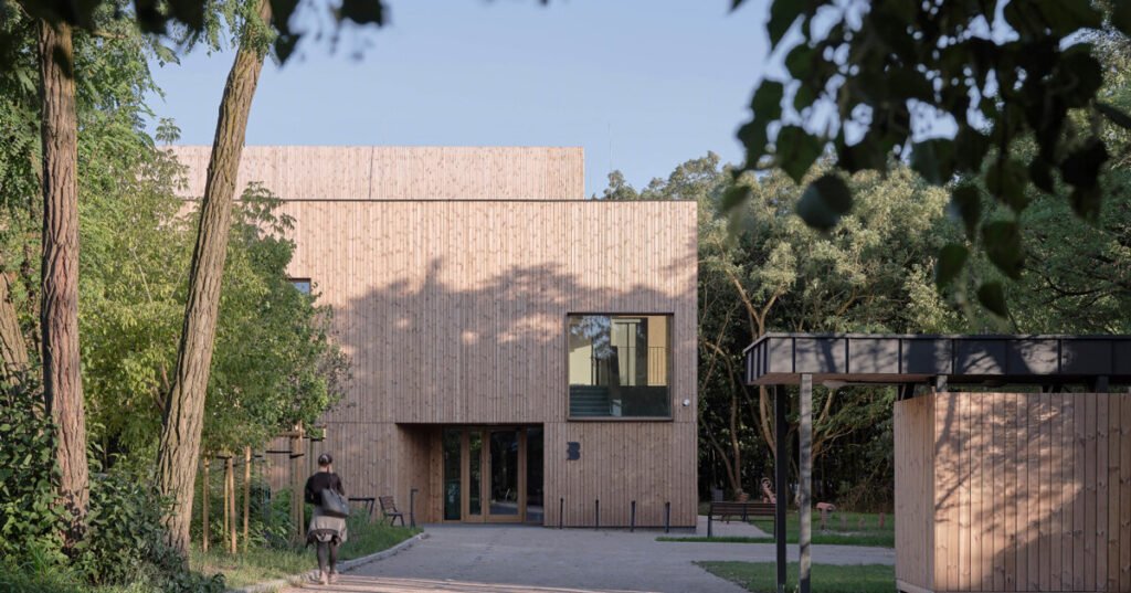 public library clad in washed timber integrates with warsaw's forest