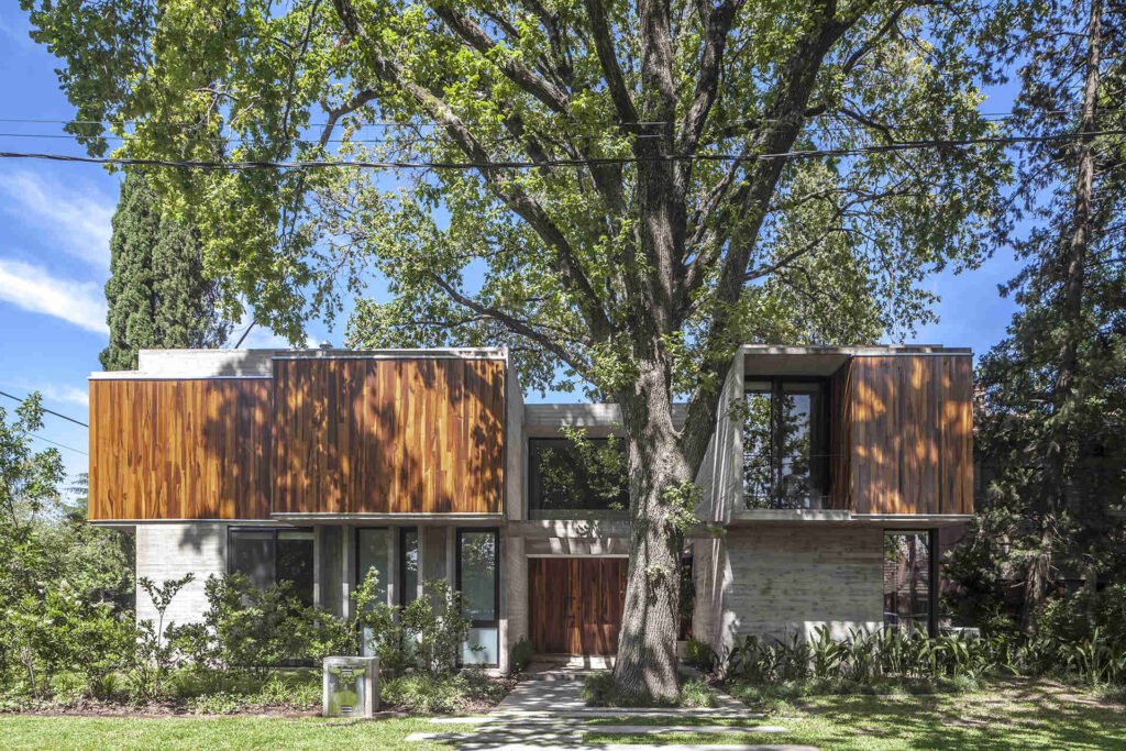 Casa Aranzazu in Buenos Aires by Besonias Almeida arquitectos is a modern concrete and wood house designed around mature trees, with large windows and a leafy corner-lot setting.