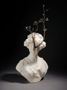 a bronze and alabaster sculpture of a branch emerging from a sculptural bust's eye